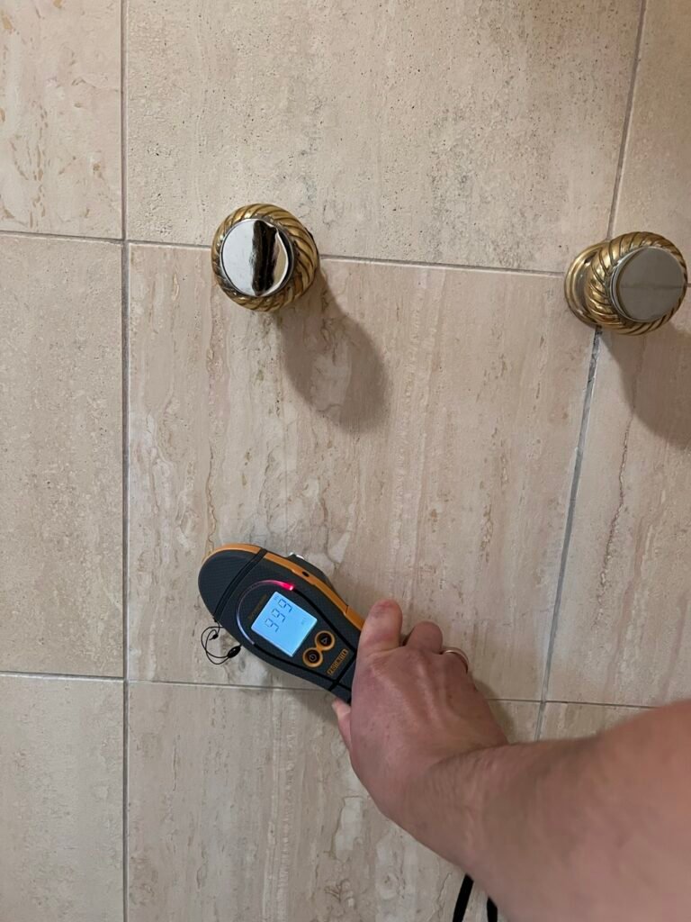 Moisture meter reading on shower tile to find a pinhole leak behind the valve in a Bel Air home