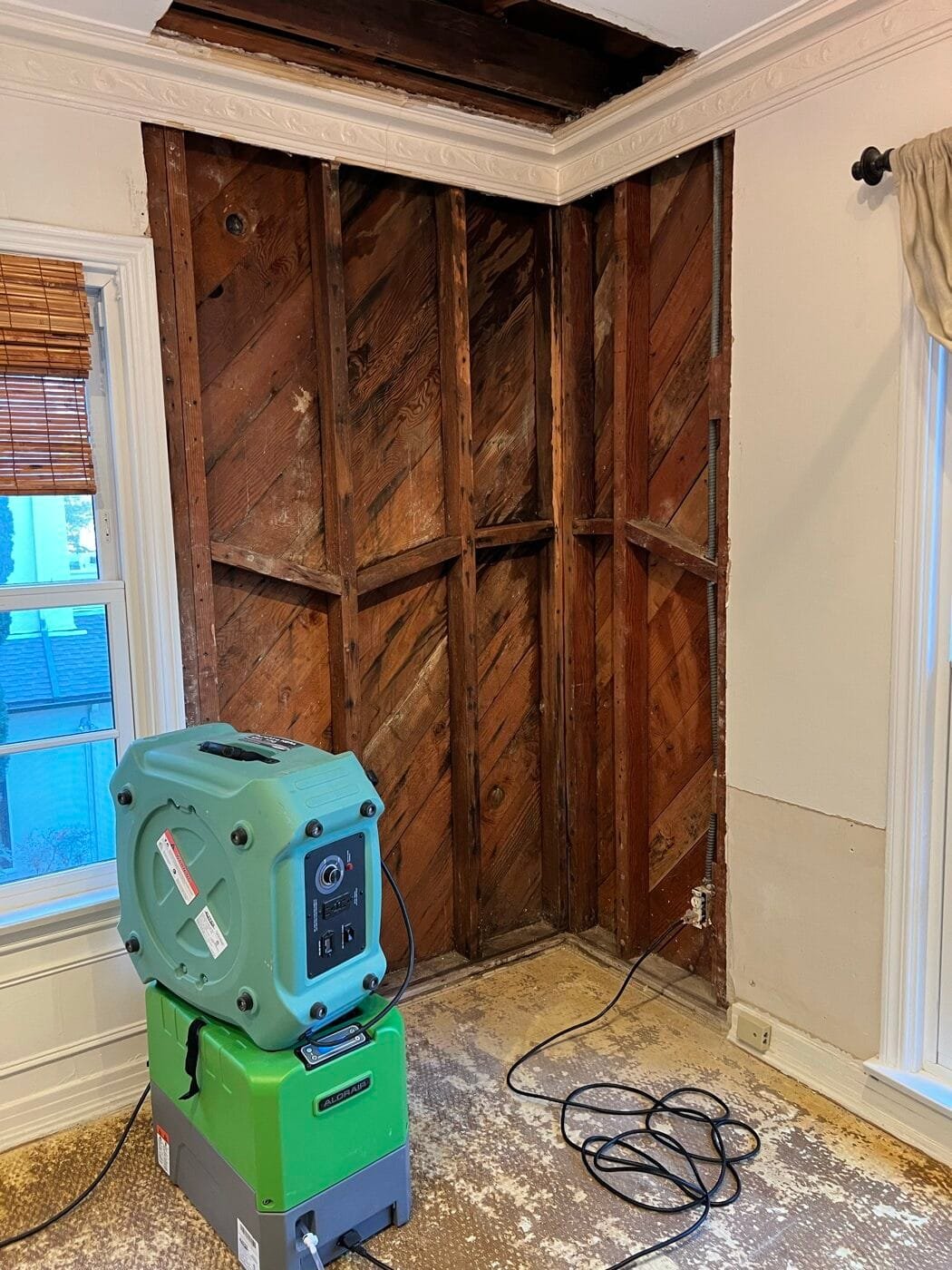 Wall opened to the original diagonal board sheathing with drying equipment in a Beverly Hills home