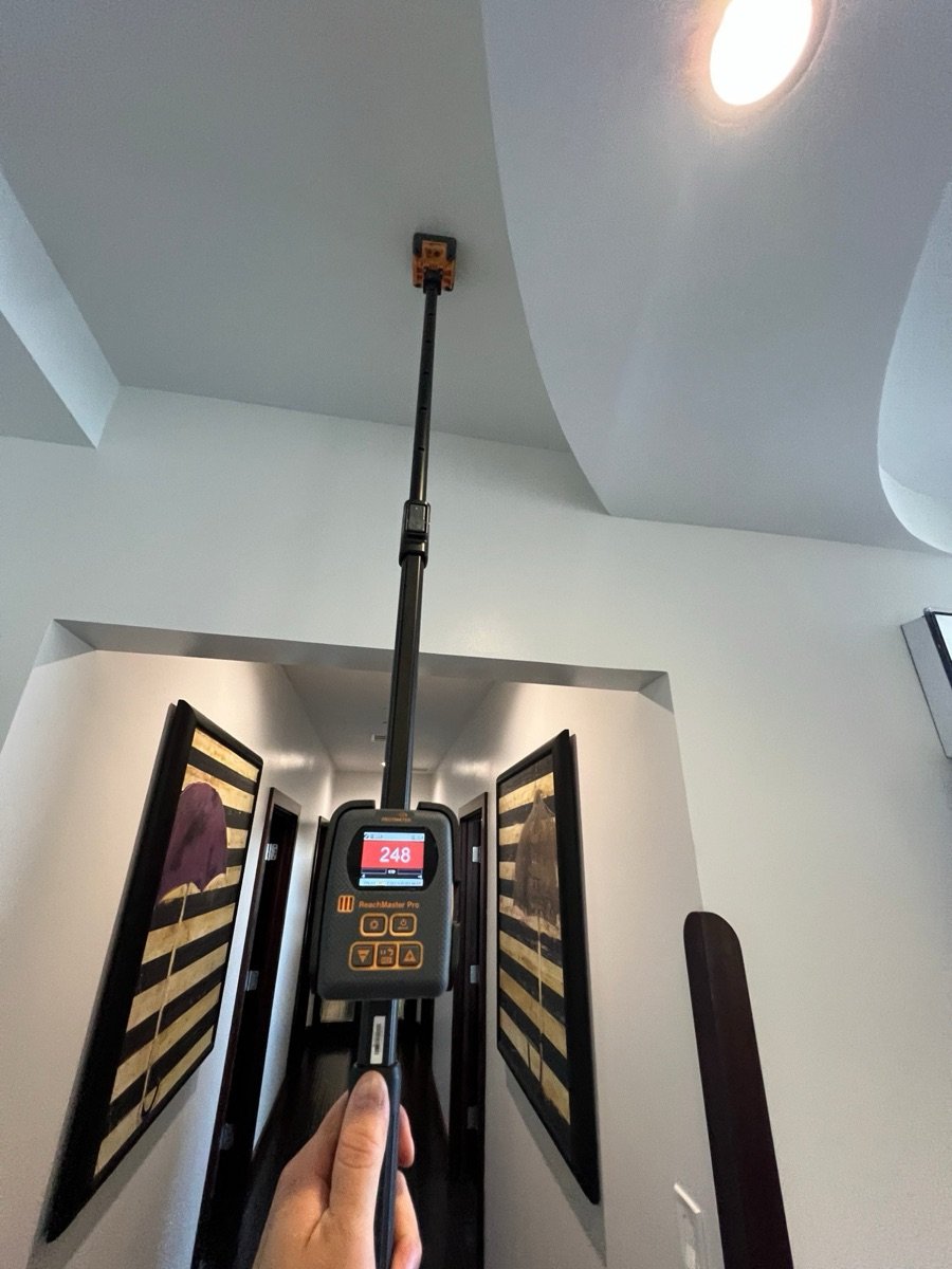 Moisture meter on a pole taking a reading on a medical office ceiling