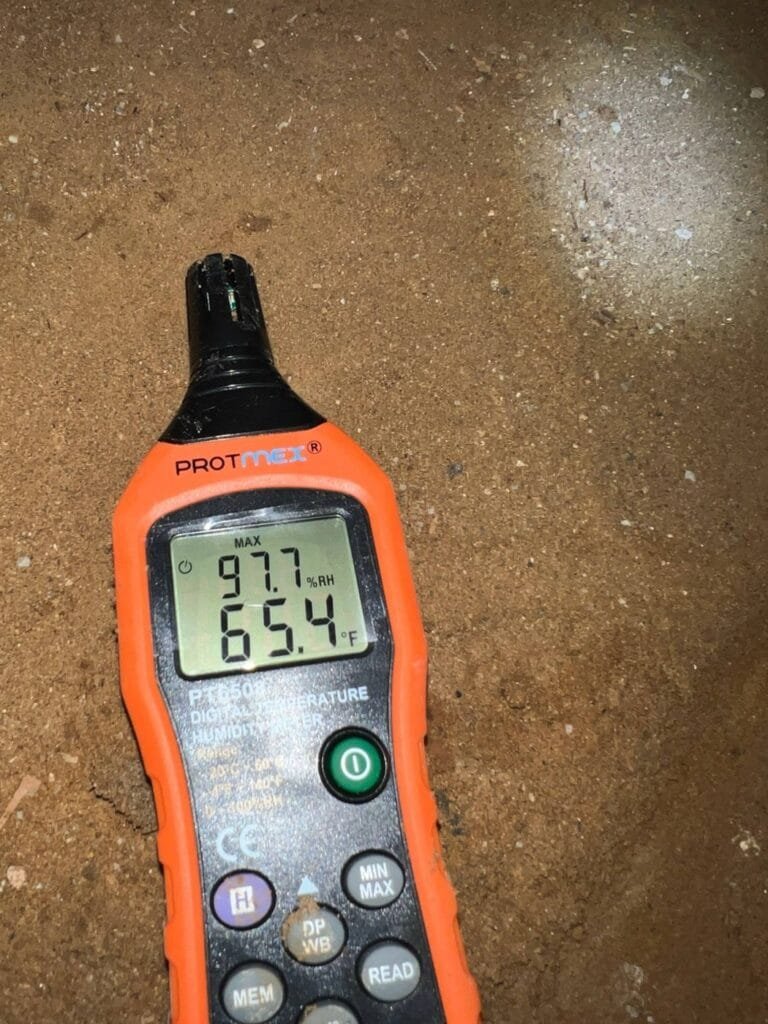 Humidity meter reading 97.7% relative humidity in a flooded crawl space in Culver City