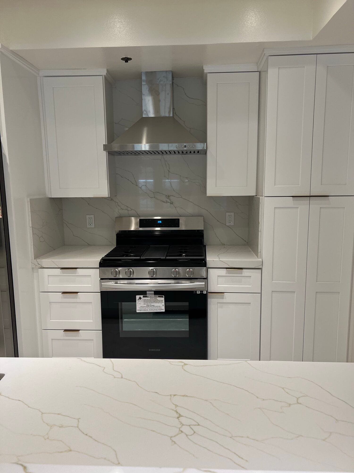 Finished kitchen rebuild with new white cabinets, range hood and quartz countertops