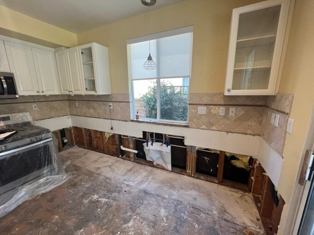 Base cabinets and flooring removed and walls opened at the bottom after a dishwasher leak in Santa Clarita