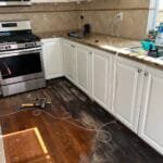 Wood floor stained black by a dishwasher leak in a Santa Clarita kitchen