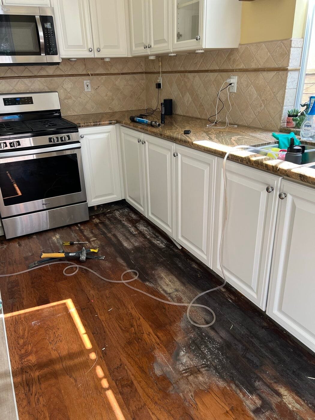 Wood floor stained black by a dishwasher leak in a Santa Clarita kitchen